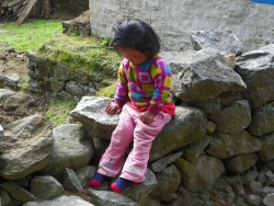 Petite fille assise sur un mur de pierres